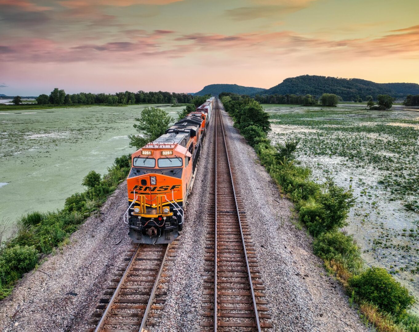 A train is traveling down the tracks near some water.